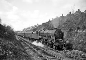 Royal Scot No.46146 'The Rifle Brigade' has stopped near the Earlsdon Avenue Bridge for a temporary restriction as it works the diverted 'The Ulster Express'  through Coventry. The houses in the background are Highland Road. Picture :- Derek Huntriss. c1959.