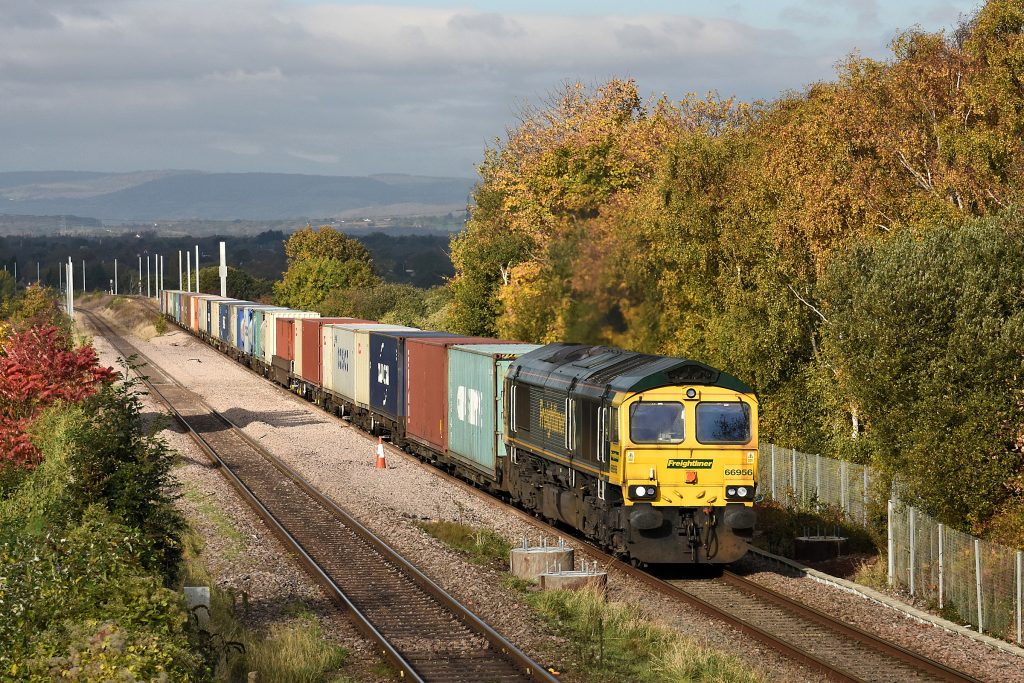 On 28th October 2016, amid Autumn colours and evidence of advancing electrification work, 66956 makes steady progress up the 1 in 100 ascent towards Patchway from the Severn Tunnel with 4O51, 09.56 Cardiff Wentloog to Southampton Freightliner.  The different gradient profiles of the up and down lines between Pilning and Patchway are of interest.  The down line on the left follows approximately the profile of the original 1863 single-track branch to New Passage Pier, whereas when the route was doubled with the opening of the Severn Tunnel in 1886, the up line was laid on a longer but less severe gradient for traffic climbing away from the tunnel.  Image credit: Stewart Jolly