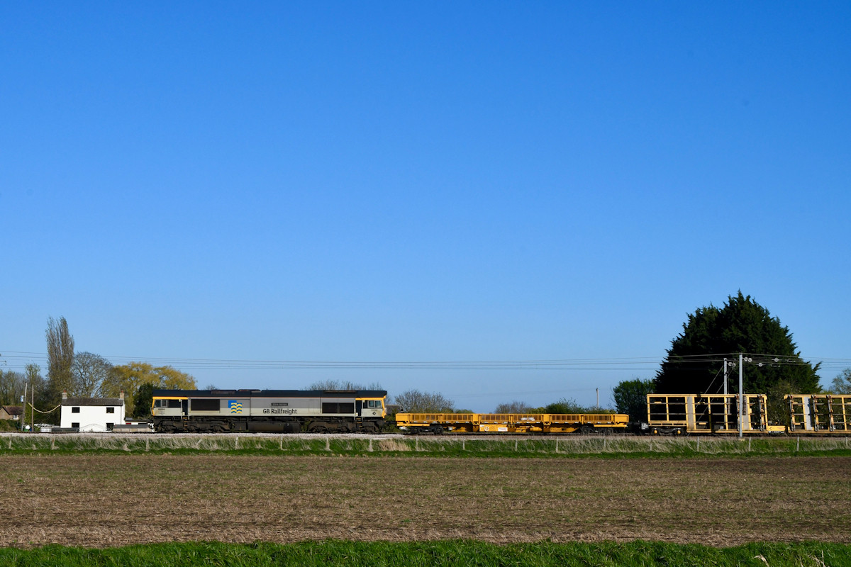 Against a backdrop of a tall Fenland sky, GB Railfreight Class 66 No. 66694 hauls 6X67, an Engineer's train from Camden Junction to Toton North Yard through Waterbeach on Tuesday 7th April 2026, following track renewal at Euston over the Easter weekend. The consist comprises 'Switch Tilter' trestle wagons, used to carry pre-fabricated pointwork vertically on its side, but which can be tilted into a horizontal position for ease of laying on location. Trestle wagons were more common when the UK manufactured wide-section steel plate, which is sadly no longer done on-shore. Photo: Michael Smyth.
