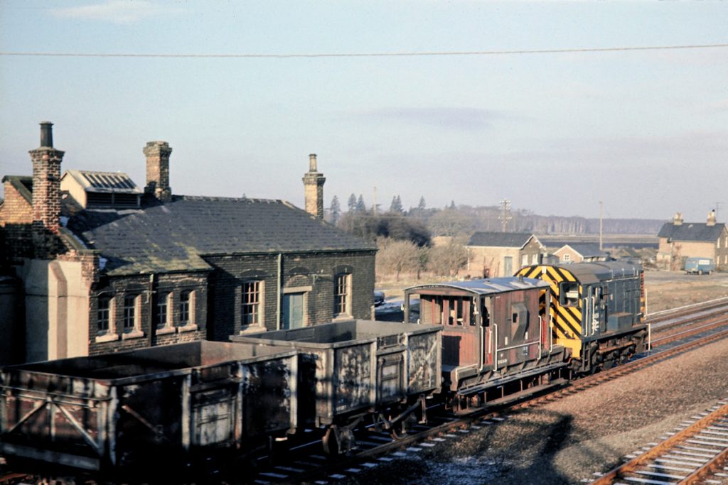 19701231-HOLME-Jc-3409-08339-Ramsey-North-Peterborough-Trip-Freight-JMT34907-John-Tolson-E3W Having arrived at Holme on 9B24 from Ramsey North on December 31st 1970, BR Class 08 no. 3409 has been down to Connington to round and is now running wrong line on the Up line, before shortly crossing over onto the Down line to return to New England. The journey was a leisurely one, with an hour and thirty-five minutes allowed for just over ten miles from Connington to New England. Photo: John Tolson, courtesy Trevor Davis.