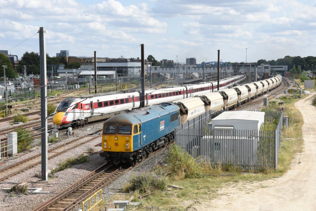 20250815-PETERBOROUGH-801222-1S21-14 GB Railfreight's magnificent Class 69s are now in regular use on the Middleton Towers sand trains. Pulling away from Peterborough station on August 15th 2025 and heading to Marholm Junction for the Joint Line, 69007 (formerly 56037) 'Richard Trevithick' accelerates North with 6E88, 12.26 Middleton Towers to Goole Glassworks as Azuma No. 801222 pulls out of Platform 5 with 1S21, 14.30 Kings Cross to Edinburgh. Photo: Alan Jones.
