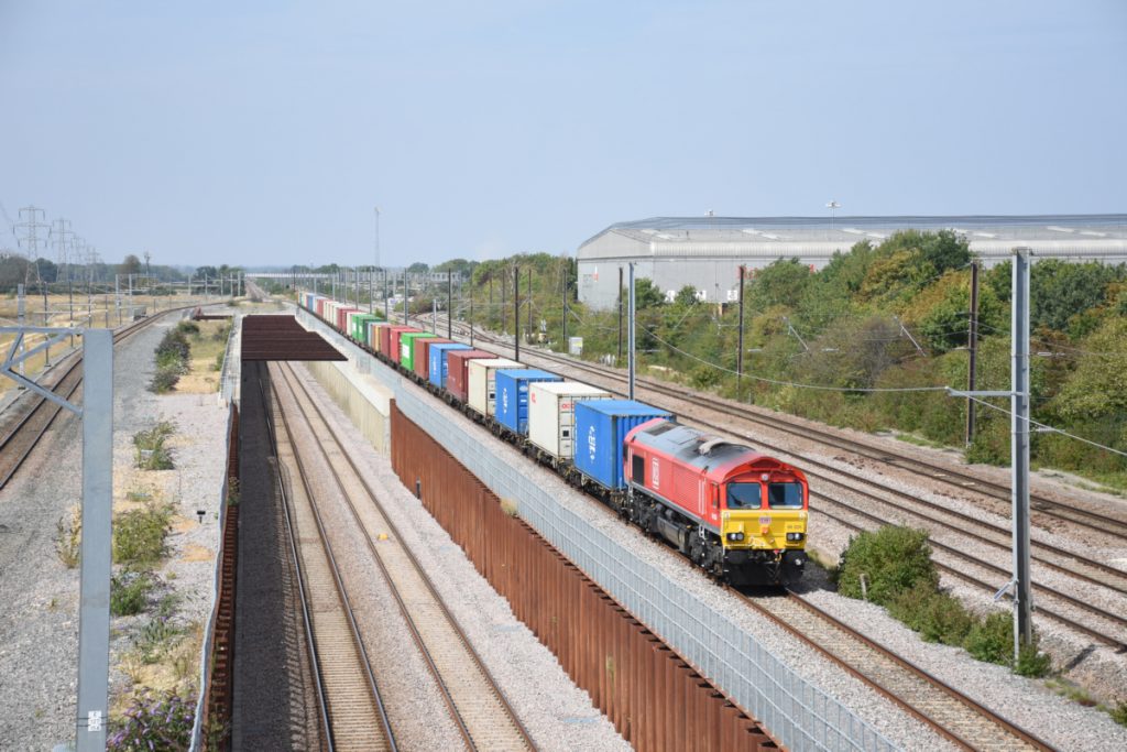 20250811-WERRINGTON-Jc-66026-4L32-09 The new dive-under lines recently constructed by Morgan Sindall at Werrington Junction are seen to good effect, as is the extensive ironwork necessary to retain the cutting walls. On a hot and hazy 11th August 2025, with flat Summer lighting, DB Class 66 No. 66026 approaches the new Marholm Junction, where the dive-under lines join the former Midland lines from Stamford, with 4L32, 09.20 Trafford Park to Felixstowe North. Photo: Alan Jones.