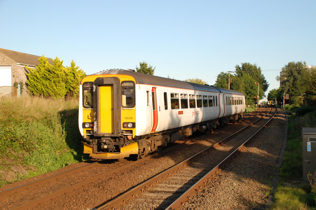 Shadows lengthen in the afternoon of Saturday September 2nd 2017 at Burnt House Crossing to the West of Cantley station as Class 156 No. 156418 slows to stop at the station with the 17.50 Norwich to Lowestoft. Pulling out of the station is 156402 on the 17.47 Yarmouth to Norwich. This is the return working of a 'rush-hour' extra from Norwich to Yarmouth which travel out via Acle and returns via Reedham. Photo: Alan Jones.