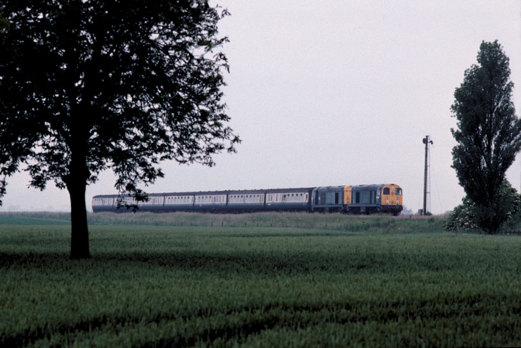 19910706-BELLWATER-Jc-2008120016-06-30-SO-Sheffield-Skegness-Alan-Jones-E4W By the early 1990s, the number of Summer Saturday trains to Skegness was beginning to reduce and Class 20s and Mark 1 stock were increasingly rare. However, July 6th 1991 did produce a pair of 20s, including one of the original Pilot Scheme locomotives, seen at Bellwater Junction as 20081 and 20016 work the 06.30 (SO) Sheffield to Skegness. Photo: Alan Jones.