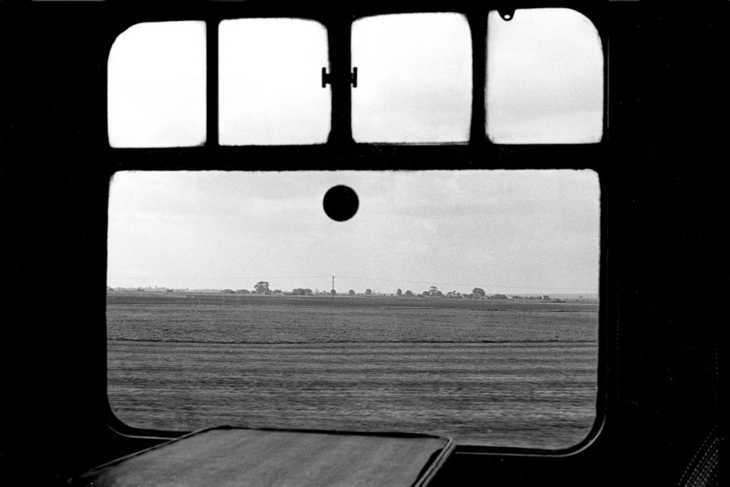 19830917-EAST-VILLE-View-from-15-35-SO-Skegness-Peterborough-Alan-Jones-E4W One of the best travelling experiences has to be from either a Tourist Second Open (TSO) or First Open (FO) BR Mark 1 carriage with Commonwealth bogies. This view from the former epitomises the photographer's memories of the Skegness line on Summer Saturdays - curled-up edges of table surface, the encrusted grime around the edges of the window panes, the smell of old tobacco (even though a non-smoking carriage!) and the flat Lincolnshire landscape. The train is the 15.35 (Summer Saturdays Only) Skegness to Peterborough, near East Ville, and is effectively an advertised empty stock working from the earlier 09.36 Kings Cross to Skegness on the last day of the season, Saturday 17th September 1983. Photo: Alan Jones.