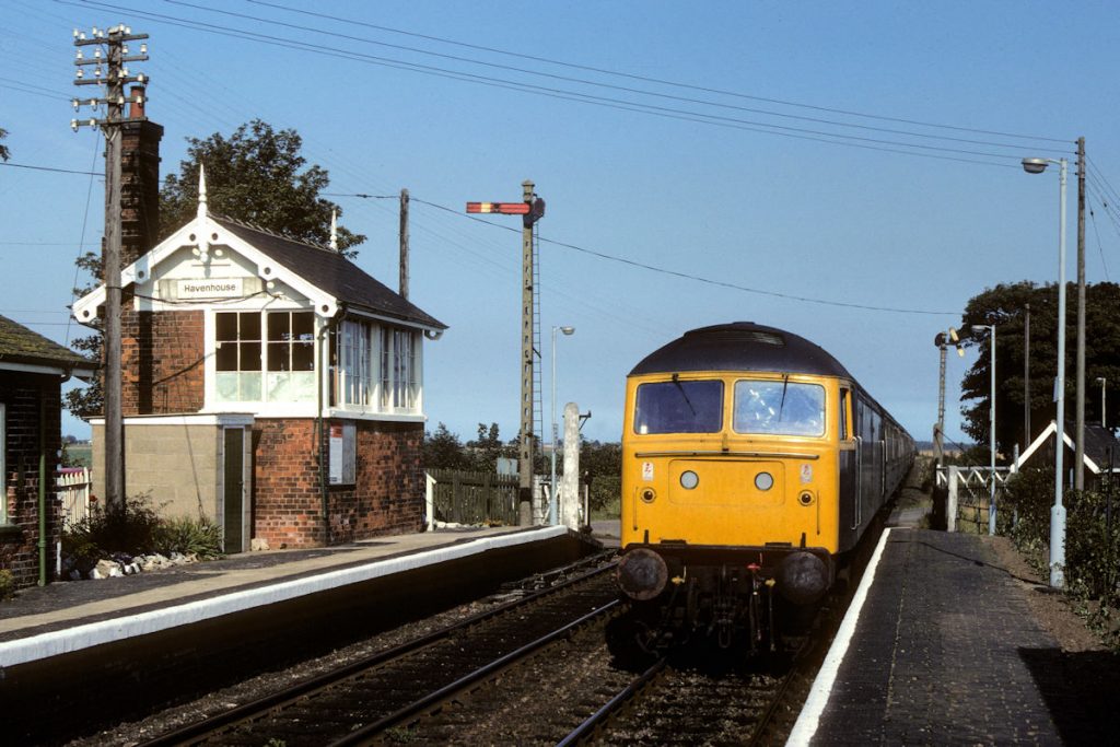 19820911-HAVENHOUSE-47144-1B60-15-35-SO-Skegness-Peterborough-2-Alan-Jones-EW Returning to Peterborough with the stock of the through Summer Saturday train from Kings Cross, Class 47 No. 47144 heads through Havenhouse with 1B60, the 15.35 from Skegness on September 11th 1982. Both metal and wooden Somersault arms were to be found on the Skegness Line, with metal versions in use on the Up and Down Home signals at Havenhouse. Photo: Alan Jones.