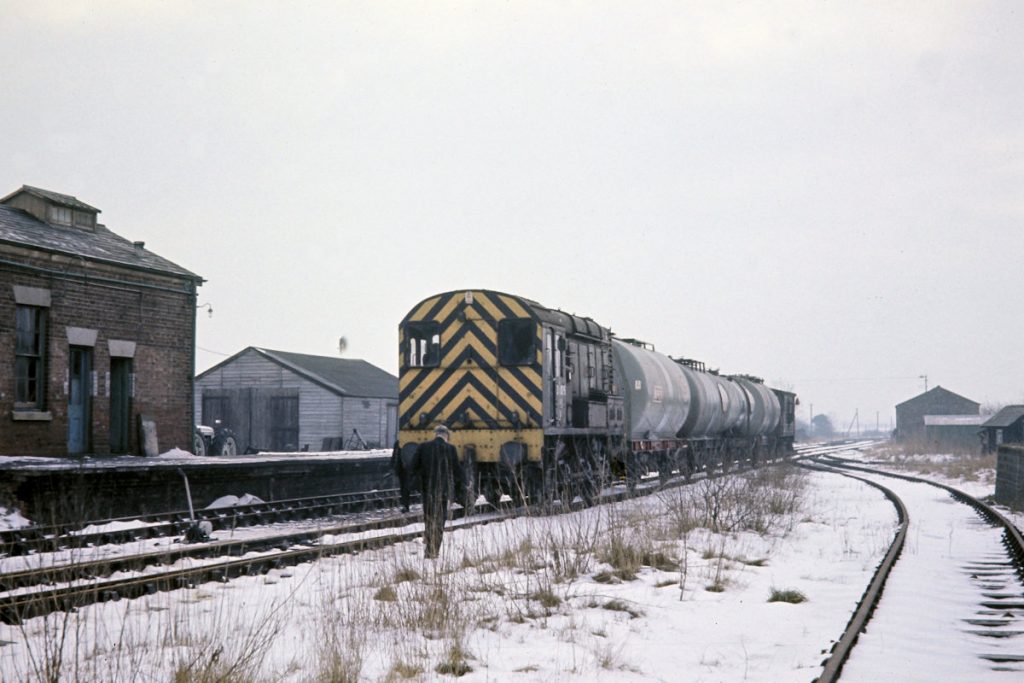 19700219-HORNCASTLE-D4075-Arrives-with-10 On Thursday 19th February 1970, Lincoln-based BR Class 10 No. D4075 has just arrived at Horncastle at 13.05 with four oil tanks on 9K77, 10.19 from Lincoln Holmes Yard, for the depot behind the station building. After arrival, D4075 uncoupled, collected a single empty oil tank from the depot, put this on to the back of the brake van, shunted the four loaded tanks, brake van and single empty into the oil depot, then uncoupled the brake van from the loaded tanks and returned to the station to wait departure at 14.03 with 9K79 to Holmes Yard. Photo: John Tolson, courtesy Trevor Davis.