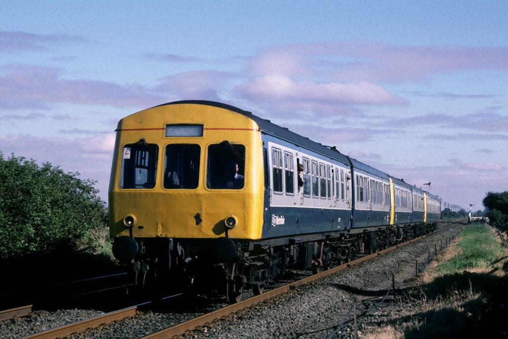 19870926-SIBSEY-E53137-09-46-Skegness-Nottingham-Alan-Jones-E3W On Summer Saturdays the usual 2-car DMU formations on the Skegness Line were often strengthened with units brought in from elsewhere. In this view at Sibsey on Saturday September 26th 1987, Neville Hill-allocated E53137 (with MetroTrain branding) is performing such a role on the 09.46 Skegness to Nottingham. Even in the 1980s, before the widespread availability of budget airlines, traffic to holiday resorts such as Skegness was reasonable and the railway played a significant part. Photo: Alan Jones.