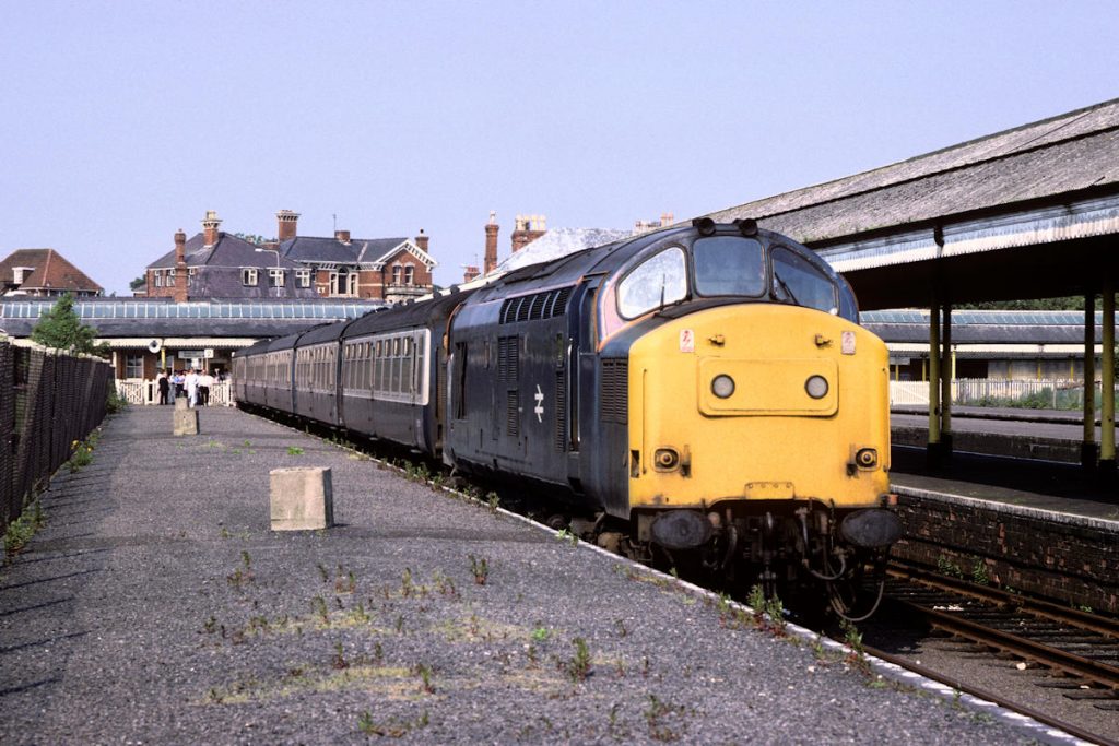 19870704-SKEGNESS-37153-Additional-to-Grantham-Alan-Jones-E4W In the late 1980s an additional Summer Saturday working was laid on from Grantham to Skegness and back using the delightfully named 'Grantham Ballast Engine' - in practice a Class 37 allocated to Civil Engineer's duties. The working made a very welcome addition to services and on Saturday July 4th 1987, 37153 waits at Platform 2 for its return run as staff prepare to let passengers board. Photo: Alan Jones.