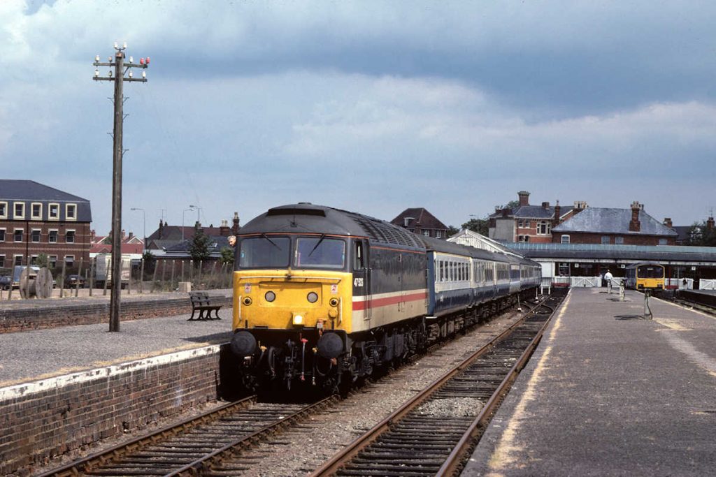 19890812-SKEGNESS-47523-13-13-SO-to-Sheffield-1-Alan-Jones-EW Enjoying a brief period of sunlight before the heavy cloud came in, the driver of 47523 checks up and down the platform prior to departure with the 13.13 (SO) to Sheffield on August 12th 1989. In 1989, there were two Summer Saturday trains to Skegness. The first left Sheffield at 06.32 and ran via Nottingham and the Grantham Avoiding Line. The second (seen here) departed at 09.19 and ran via the Great Central and the Joint Line to arrive in Skegness at 12.43. It then had a very short run round of 30 minutes before returning to Sheffield at 13.13, again via the Joint Line and the GC. Photo: Alan Jones.