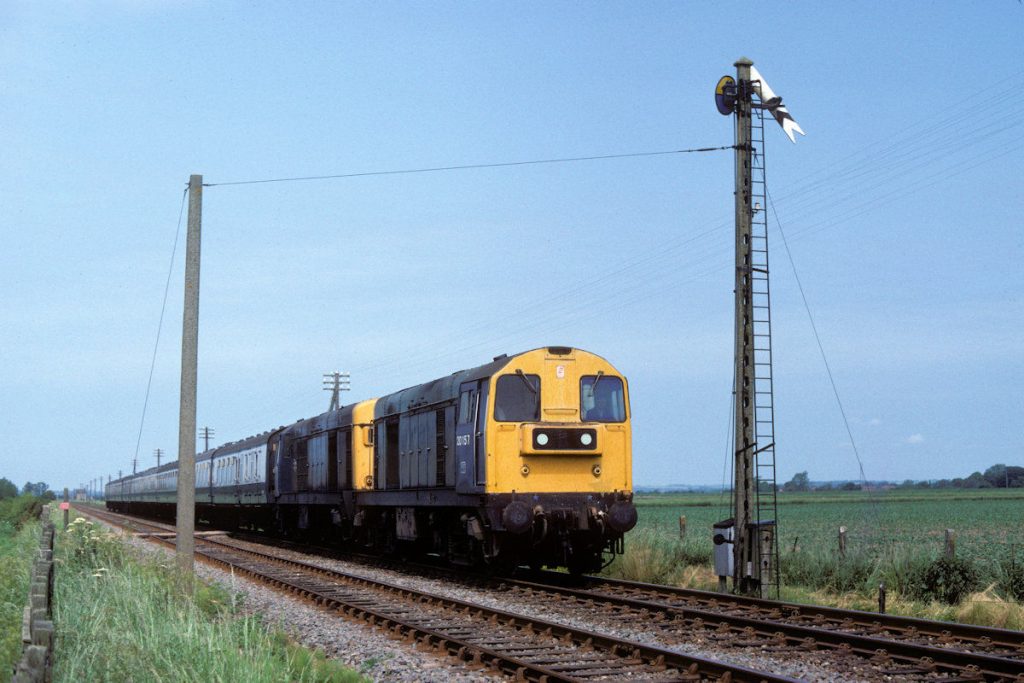 19830625-WAINFLEET-2015720135-1E86-08-38-SO-Leicester-Skegness-4-Alan-Jones-EW A view that perhaps epitomises the Skegness in the early 80s: a pair of Toton Class 20s passing a Somersault signal on the Leicester to Skegness, formed entirely of Mark 1 stock. The date is June 25th 1982, the location is Wainfleet's Down Distant and the locomotives are 20157 and 20135. The former was a lifelong Toton resident, whilst 20135 began life at Bescot, transferring to Toton in October 1969 where it remained for its BR service. Photo: Alan Jones.