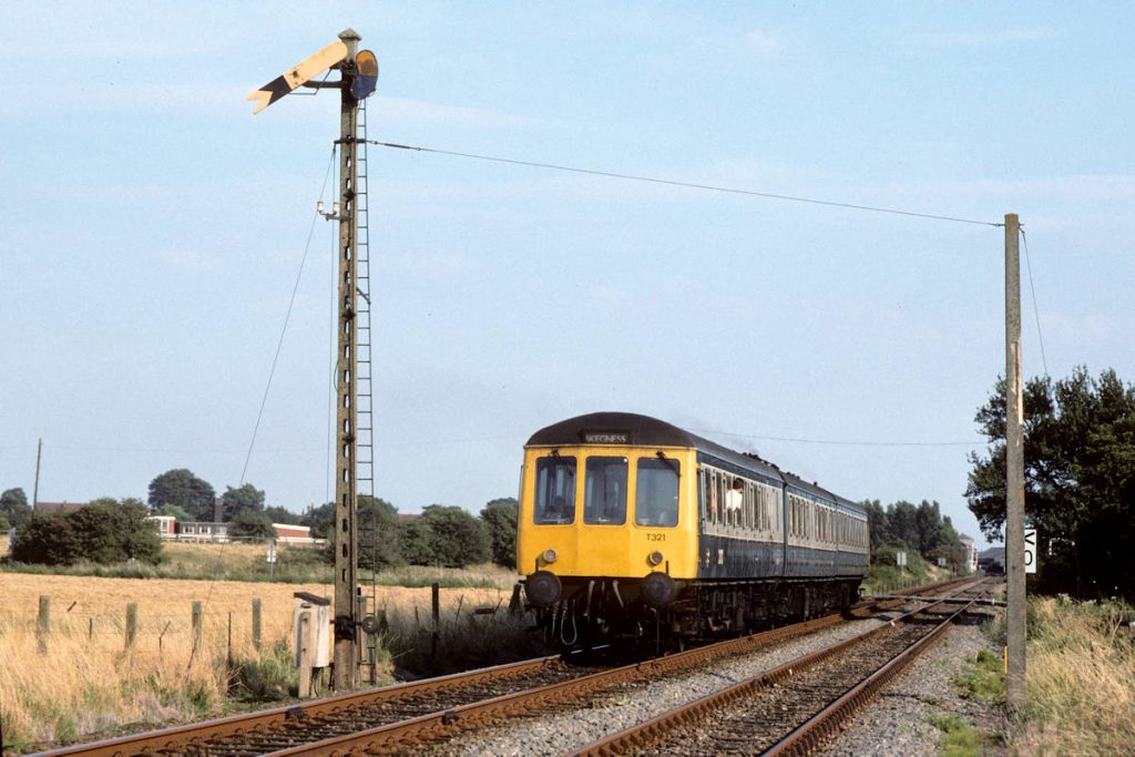 19890819-WAINFLEET-M53854M59723M53907-14-18-Derby-Skegness-EW The numerous foot crossings and low fences on the Skegness Line in the 1980s made photography a very simple and enjoyable activity. From one of the crossings to the West of Wainfleet station, the afternoon sun illuminates the rear end of Tyseley Class 116 set T321 (53854+59723+53907) as it slows for its station stop with the 14.18 Derby to Skegness on August 19th 1989. Photo: Alan Jones.