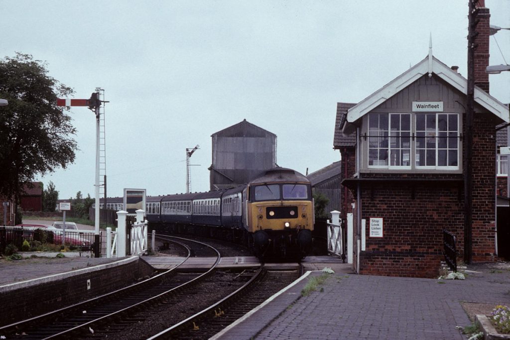19890909-WAINFLEET-47465-12-52-SO-Skegness-Leeds-Alan-Jones-E3W Like Firsby, there is a 15 mph speed restriction round the very tight curve at Wainfleet. With flanges squealing, Brush Class 47 No. 47465 takes it slowly round the curve and into Wainfleet station on a very dull and gloomy 9th September 1989 with the 12.52 (SO) Skegness to Leeds. Photo: Alan Jones.