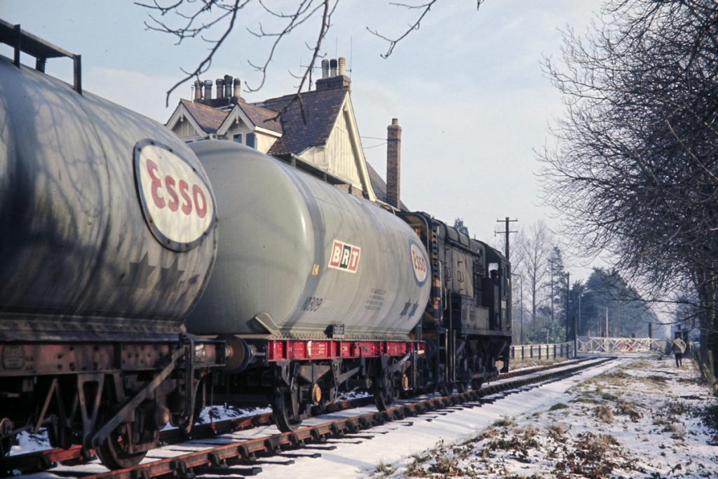 19700219-WOODHALL-SPA-D4075-10 On February 19th 1970, BR Class 10 No. D4075 slows for the level crossing with Station Road/The Broadway just before the former station in Woodhall Spa with 9K77, the 10.19 (SX) Lincoln Holmes Yard to Horncastle, comprising four Esso tanks. Woodhall Spa is most famously known for its Second World War RAF base which was home to 617 Squadron and the Lancasters that carried out the Dam Busters raid. Photo: John Tolson, courtesy Trevor Davis.