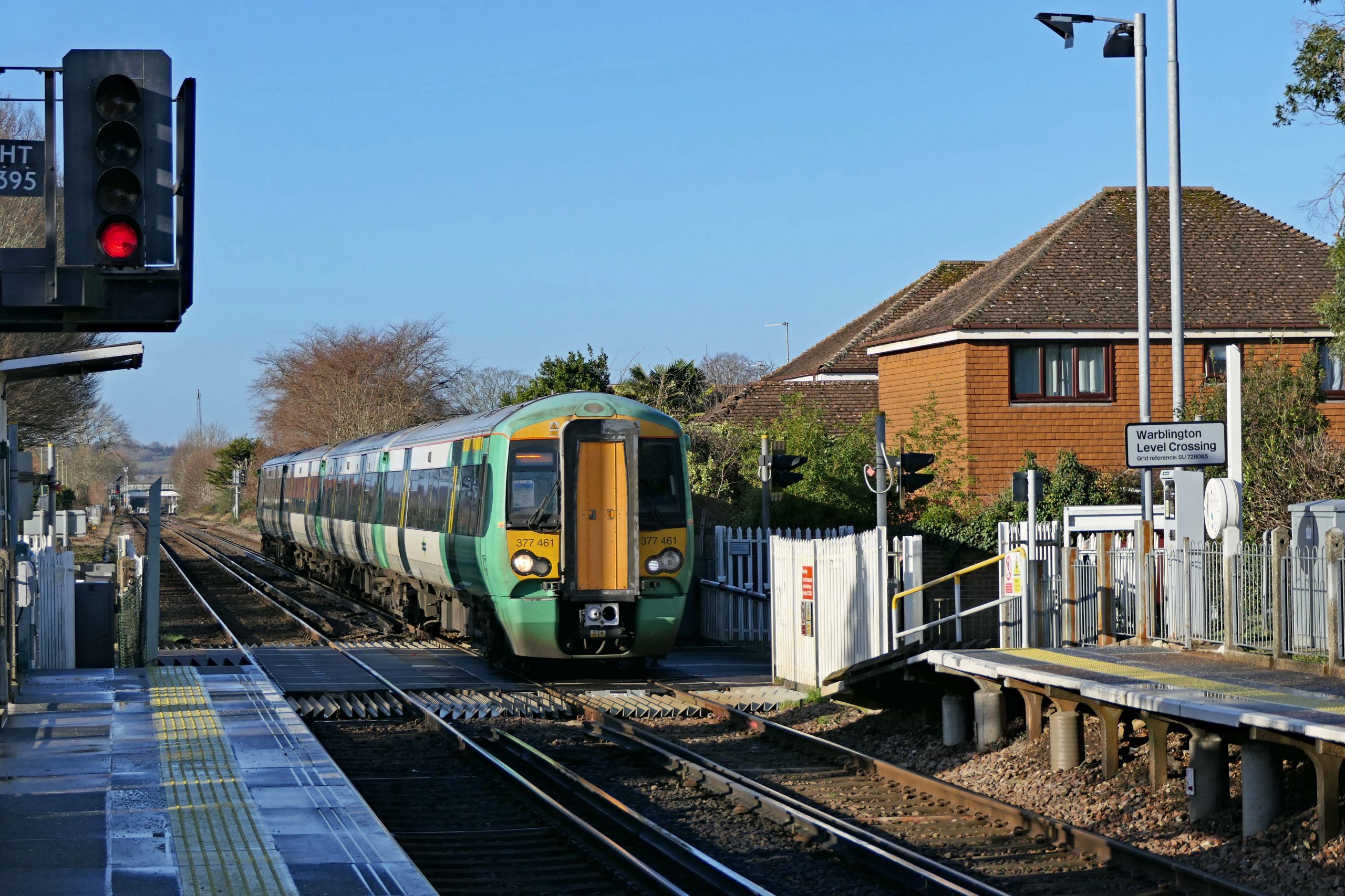 Southern Class 377 461 passes over the pedestrian and road crossing at Warblington, Thursday 20 January 2022.