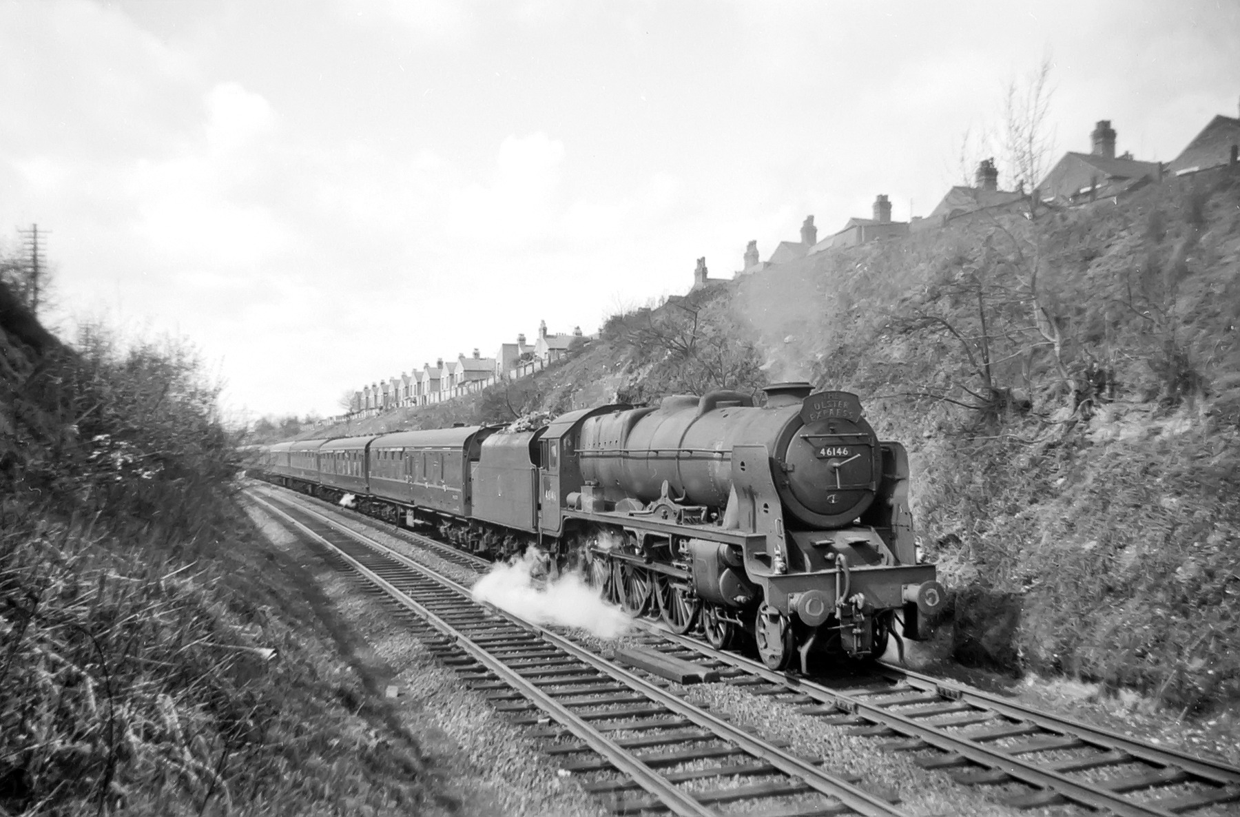 Royal Scot No.46146 'The Rifle Brigade' has stopped near the Earlsdon Avenue bridge for a temporary restriction as it works the diverted 'The Ulster Express' through Coventry. Houses in the background are in Highland Road. c1959.